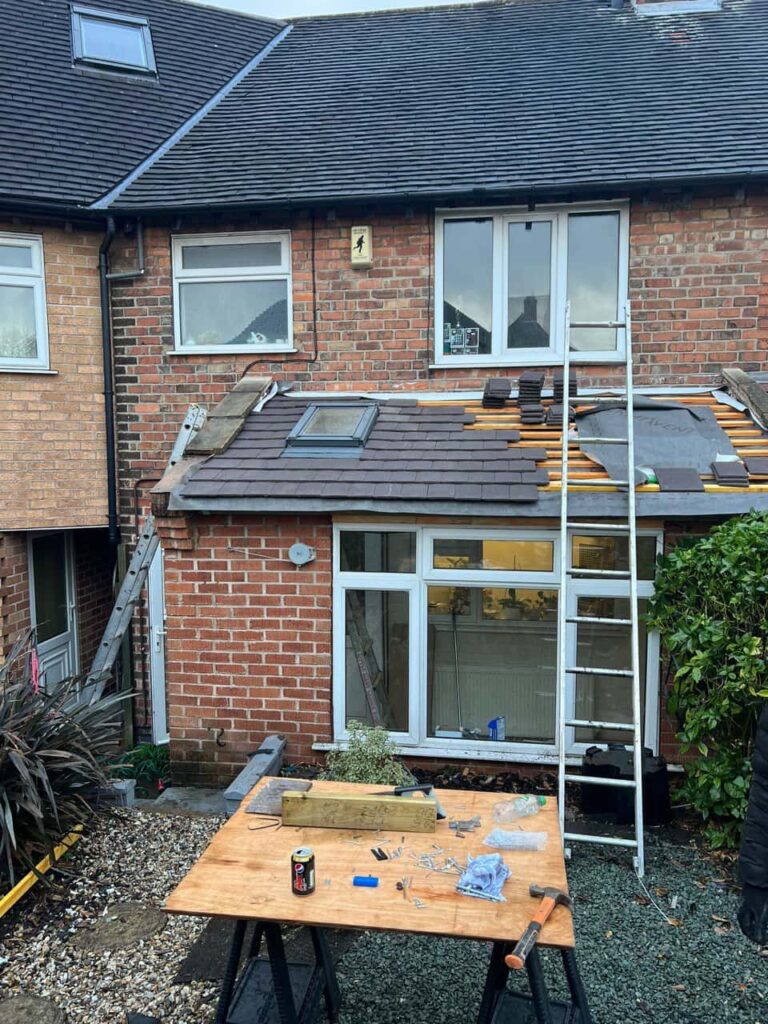 This is a photo of a roof extension that is having new roof tiles installed. This is a photo taken from the roof ridge looking down a tiled pitched roof on to a flat roof. Works carried out by Alfreton Roofing Repairs